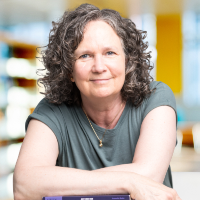 Wiebke abgestützt auf Bücherstapel, schaut ruhig und selbstbewusst